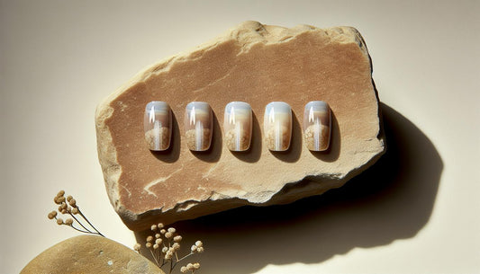 Nahaufnahme von fünf kurzen Nude-Ombre Gelnägeln mit feiner weißer Längslinie auf sandfarbenem Naturstein, dezente pinke Blüte und schwarzer Keramikakzent – sommer gelnägel